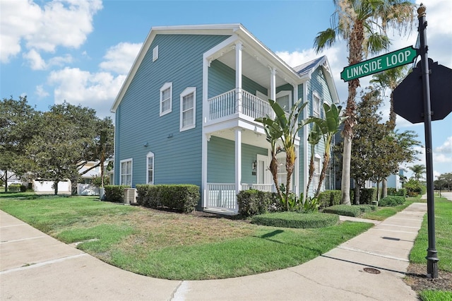 view of side of home featuring a yard, a balcony, and central AC