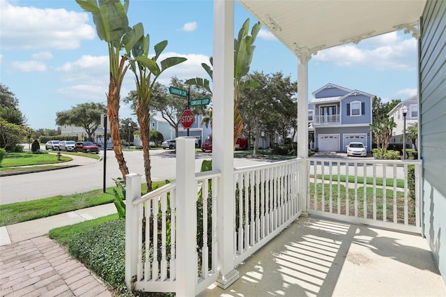 view of patio / terrace featuring a porch, a residential view, and driveway