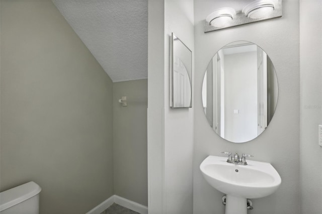 bathroom featuring a textured ceiling, toilet, and sink