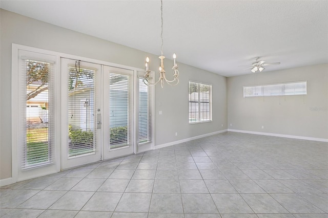 tiled spare room featuring a textured ceiling, ceiling fan with notable chandelier, and plenty of natural light