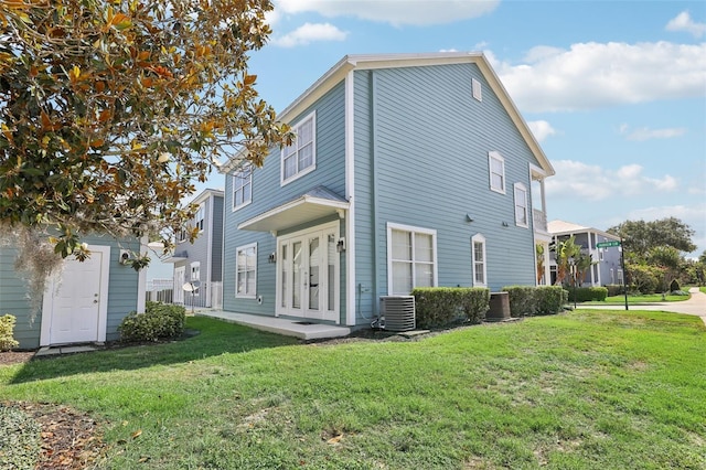 back of property with central AC and a lawn