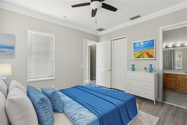 bedroom featuring light wood finished floors, a closet, visible vents, and crown molding