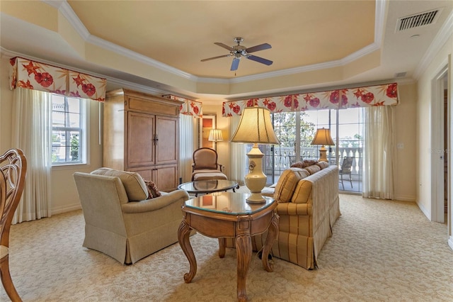 carpeted living room featuring ornamental molding, ceiling fan, and a tray ceiling