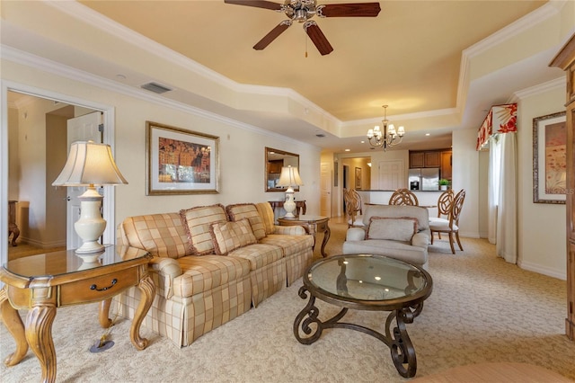 carpeted living room with crown molding, ceiling fan with notable chandelier, and a tray ceiling