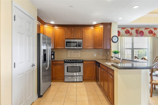 kitchen with kitchen peninsula, light tile floors, dark stone countertops, backsplash, and stainless steel appliances