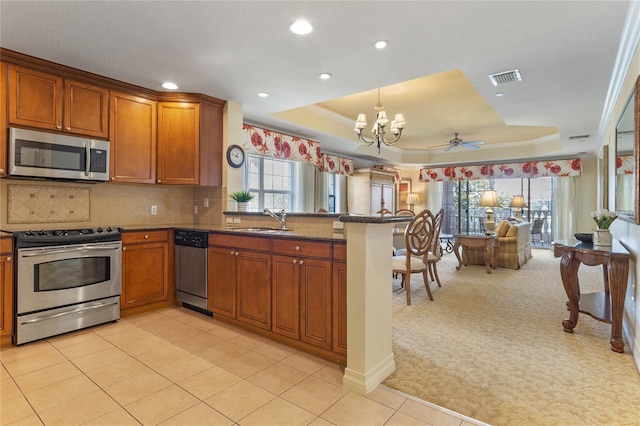 kitchen featuring kitchen peninsula, stainless steel appliances, light colored carpet, and a tray ceiling