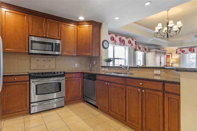 kitchen with a chandelier, plenty of natural light, a tray ceiling, and appliances with stainless steel finishes