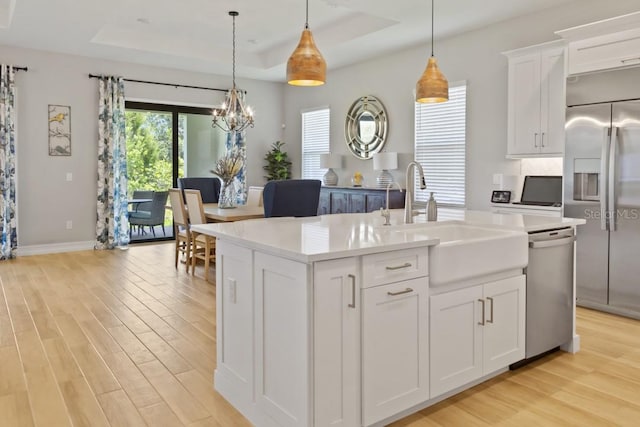 kitchen with pendant lighting, light hardwood / wood-style floors, a center island with sink, and appliances with stainless steel finishes