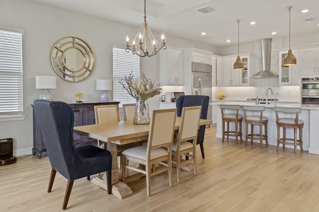 dining room with a chandelier, light wood-type flooring, and sink