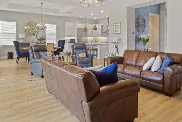 living room featuring a tray ceiling, a wealth of natural light, and light hardwood / wood-style flooring