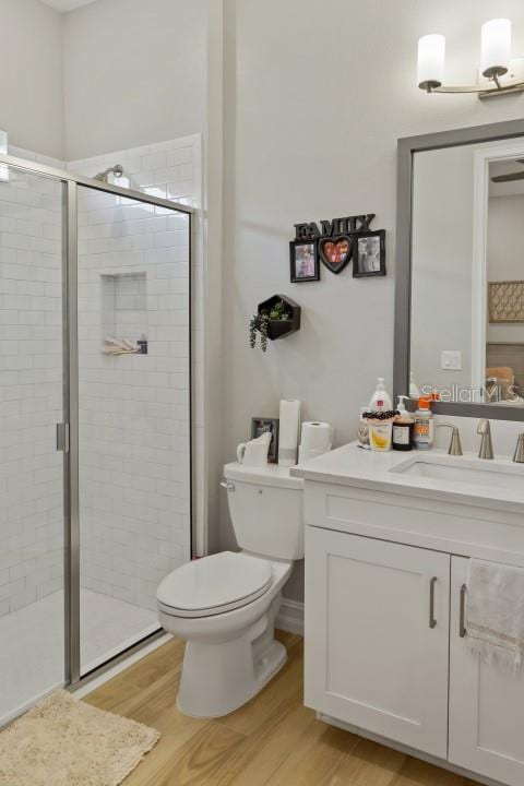 bathroom featuring wood-type flooring, vanity, toilet, and a shower with shower door