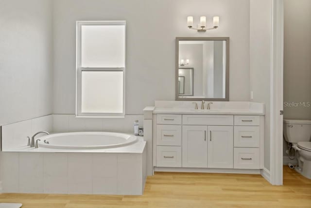 bathroom with vanity, hardwood / wood-style flooring, toilet, and tiled tub