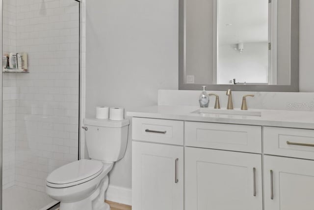 bathroom with vanity, toilet, and tiled shower