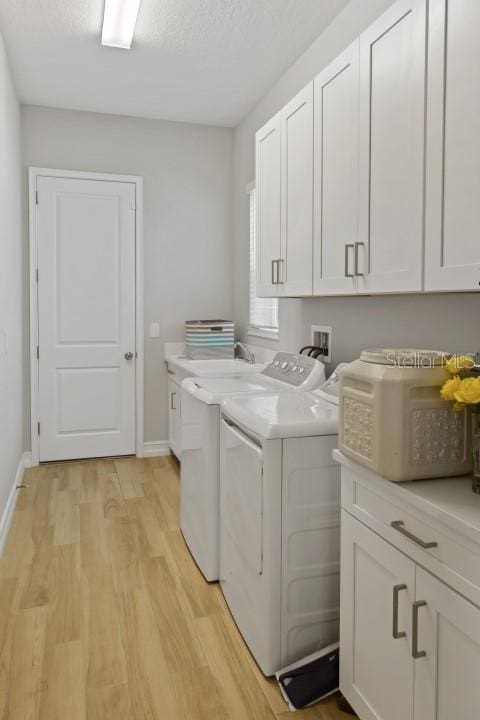 laundry room featuring light hardwood / wood-style floors, cabinets, and independent washer and dryer