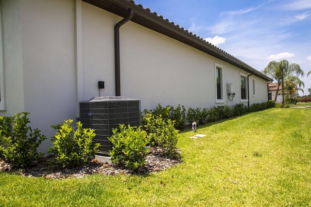 view of side of property with central AC unit and a yard