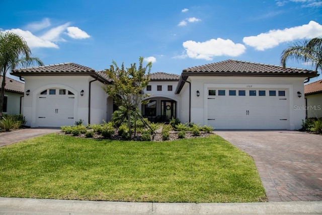 mediterranean / spanish house with a garage and a front lawn