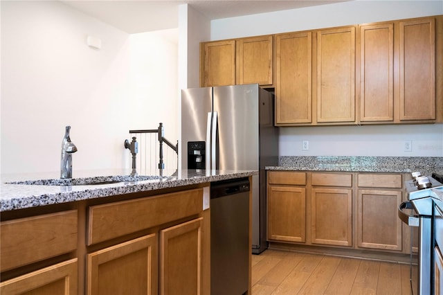 kitchen with range, light hardwood / wood-style flooring, stone countertops, sink, and stainless steel dishwasher