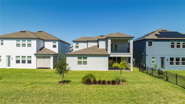 rear view of house featuring solar panels, a yard, and a balcony