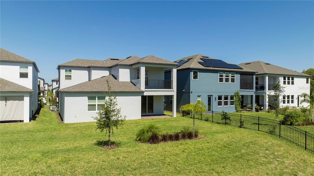 back of property with a balcony, a yard, and solar panels