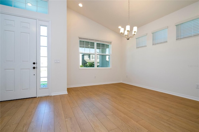 foyer featuring high vaulted ceiling, hardwood / wood-style floors, and a chandelier