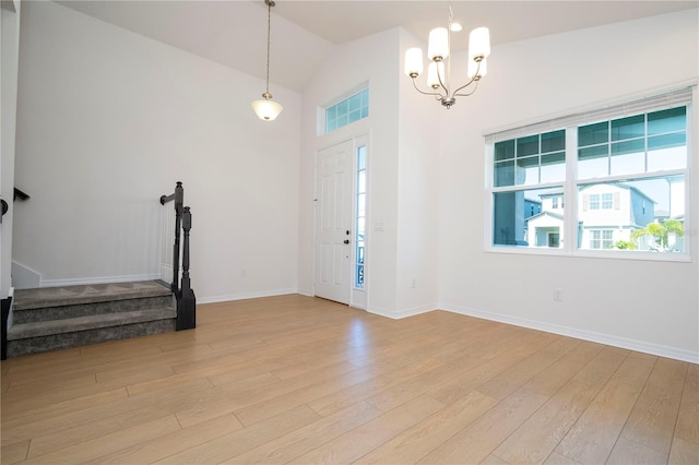 foyer entrance with a chandelier, light hardwood / wood-style flooring, and high vaulted ceiling