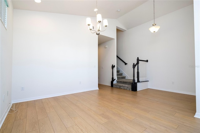 unfurnished room featuring light hardwood / wood-style flooring, high vaulted ceiling, and a notable chandelier