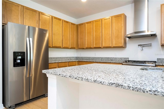 kitchen featuring light hardwood / wood-style flooring, stainless steel refrigerator with ice dispenser, light stone countertops, and wall chimney range hood