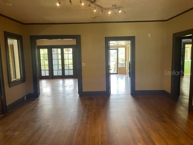 spare room featuring crown molding, dark wood-type flooring, and a textured ceiling