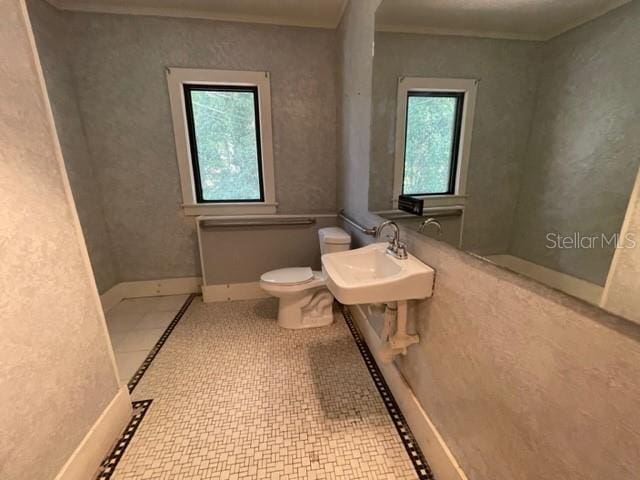 bathroom with toilet, tile patterned floors, a healthy amount of sunlight, and sink