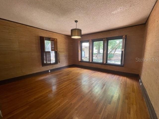 unfurnished room with hardwood / wood-style flooring and a textured ceiling