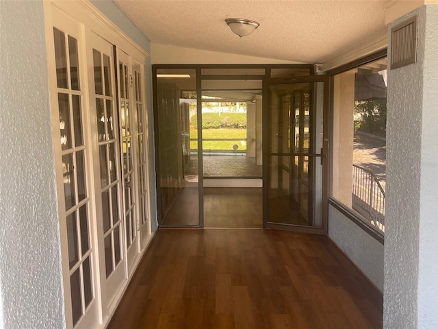 doorway with french doors, a textured ceiling, dark hardwood / wood-style floors, and vaulted ceiling