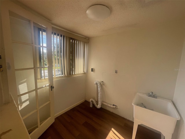 laundry area with dark hardwood / wood-style flooring and a textured ceiling