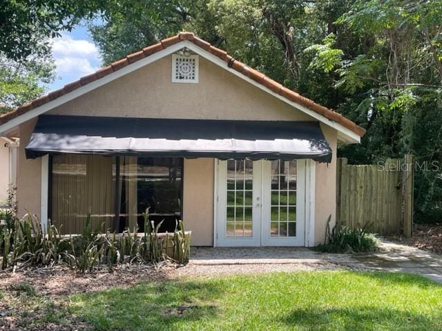 back of property with a yard and french doors