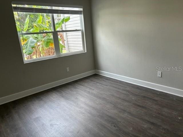 spare room with a wealth of natural light and dark hardwood / wood-style flooring