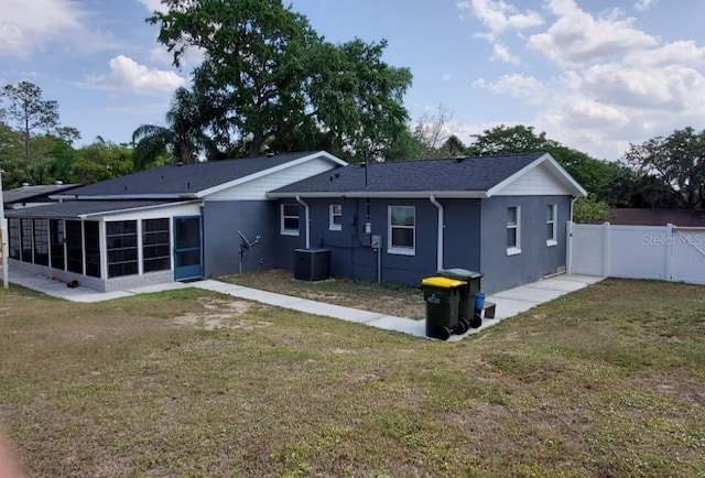 rear view of house featuring a sunroom, central air condition unit, and a yard