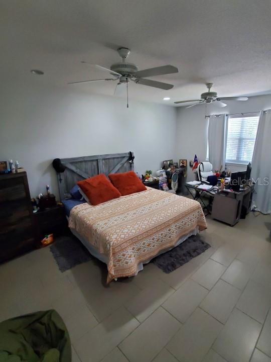 tiled bedroom featuring ceiling fan