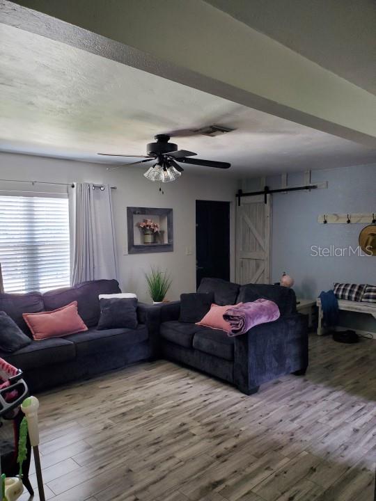 living room featuring a barn door, light hardwood / wood-style floors, and ceiling fan