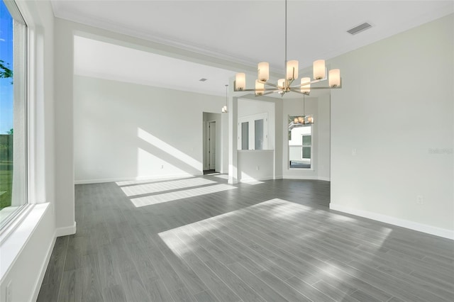 spare room with a notable chandelier, dark wood-type flooring, and crown molding