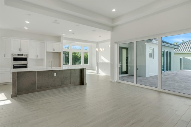 kitchen with a spacious island, white cabinetry, light wood-type flooring, and pendant lighting