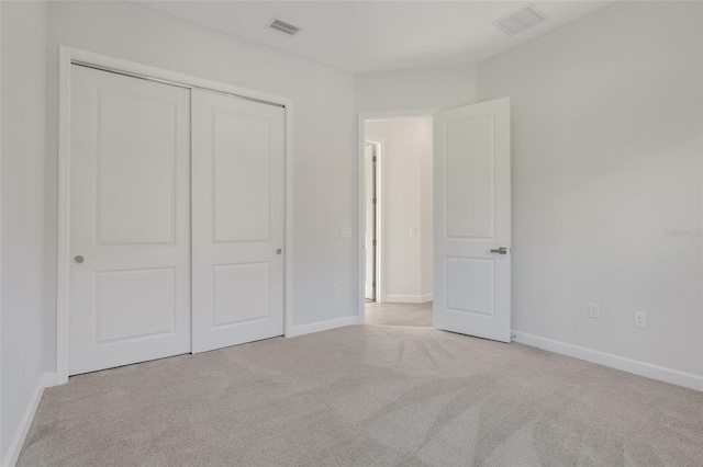 unfurnished bedroom featuring light carpet and a closet