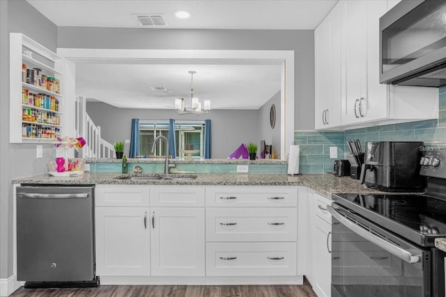 kitchen with sink, dark hardwood / wood-style flooring, stainless steel appliances, a notable chandelier, and white cabinetry