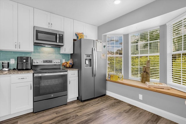 kitchen featuring dark hardwood / wood-style floors, backsplash, appliances with stainless steel finishes, and white cabinetry