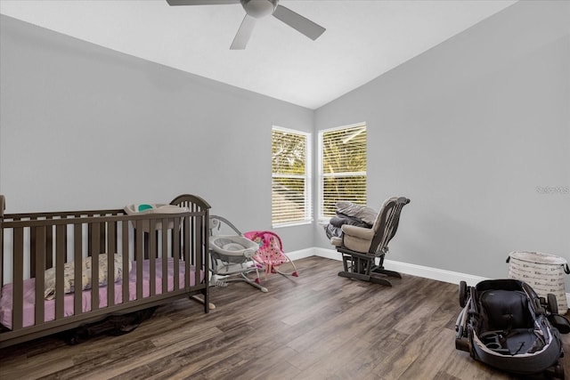 bedroom featuring ceiling fan, dark wood-type flooring, vaulted ceiling, and a crib