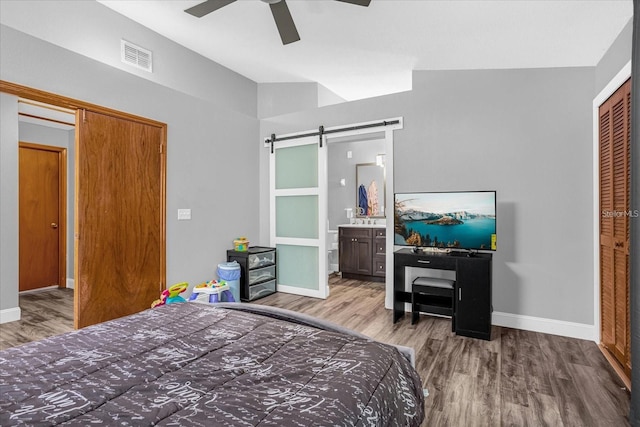 bedroom with a barn door, a closet, ceiling fan, and light wood-type flooring