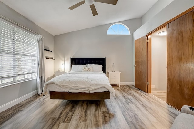 bedroom with multiple windows, light hardwood / wood-style floors, ceiling fan, and vaulted ceiling