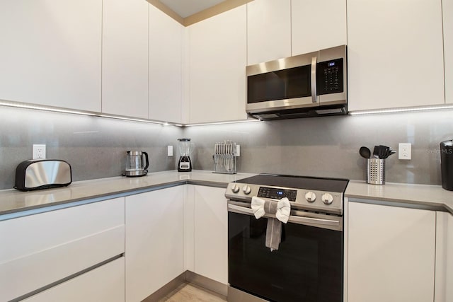 kitchen with white cabinets, backsplash, and stainless steel appliances