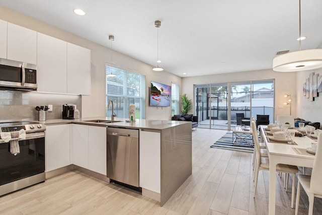 kitchen featuring white cabinets, appliances with stainless steel finishes, plenty of natural light, and pendant lighting