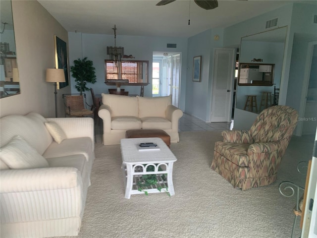 living room featuring light carpet and ceiling fan with notable chandelier