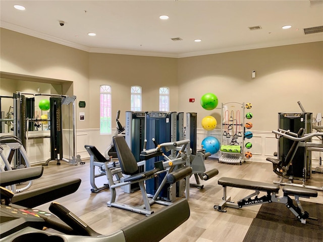 gym with light hardwood / wood-style floors and ornamental molding