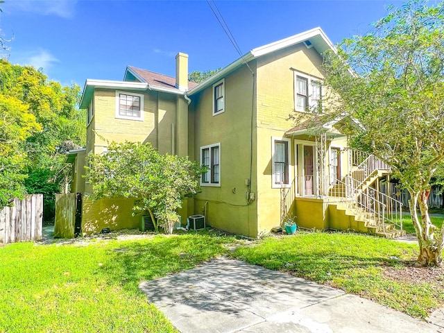 back of house featuring a lawn and central AC